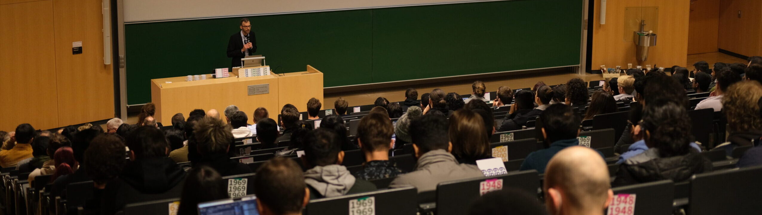 Semesterinfos_2048x580px Bild von Studierenden in Hörsaal mit Überschrift "See you online!"